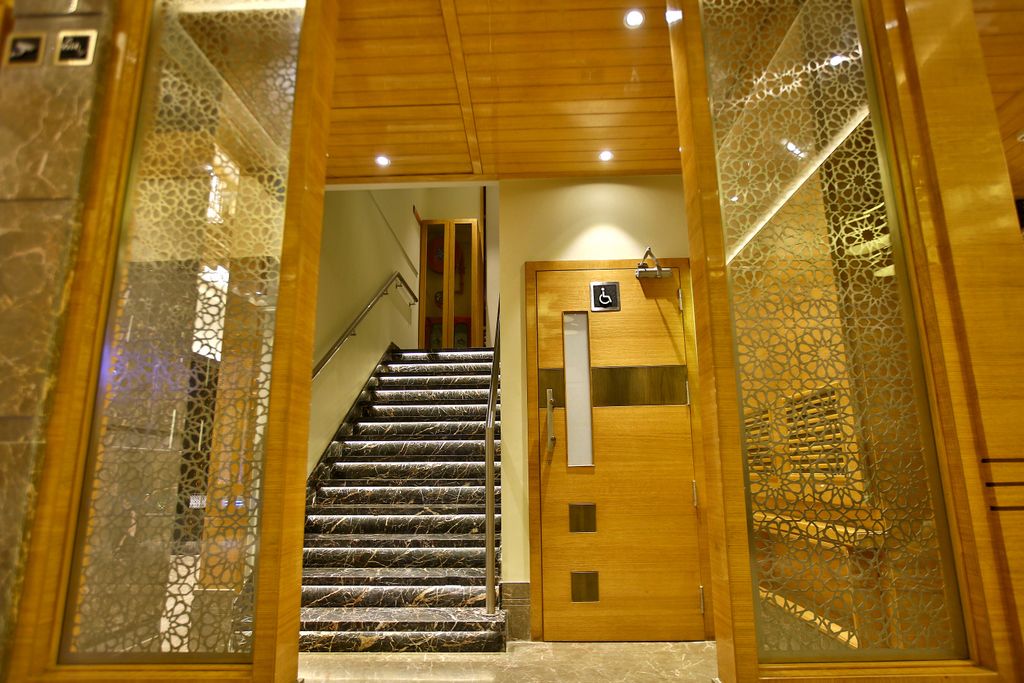 A staircase with a wooden door and a wheelchair accessibility sign.