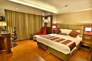 Habitación de hotel con una cama grande, un escritorio, una silla y una lámpara.