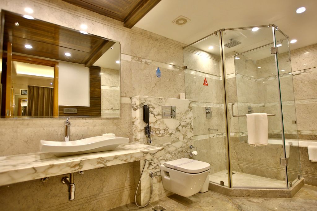 A modern bathroom with a marble sink, toilet, and glass-enclosed shower.