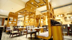 Eine moderne Hotelhalle mit Holzwandverkleidung, mehreren Essbereichen und einer zentralen Sitzecke mit einer Couch.