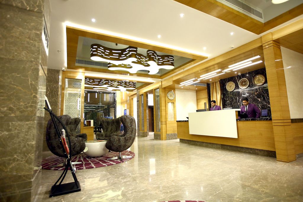 A hotel reception area with a marble floor, a reception desk, and a seating area with a unique chair design.