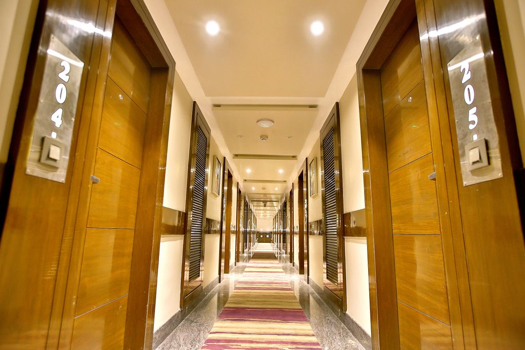 Een hotelgang met houten deuren, genummerd 204 en 205, die naar kamers leiden.