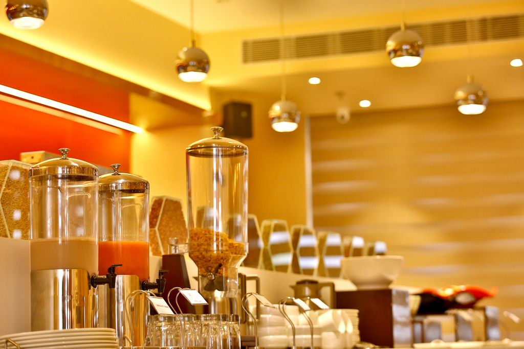A breakfast buffet setup with various food dispensers and glassware.