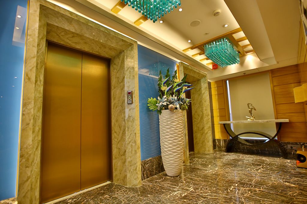 A modern elevator with a marble wall and a large potted plant beside it.