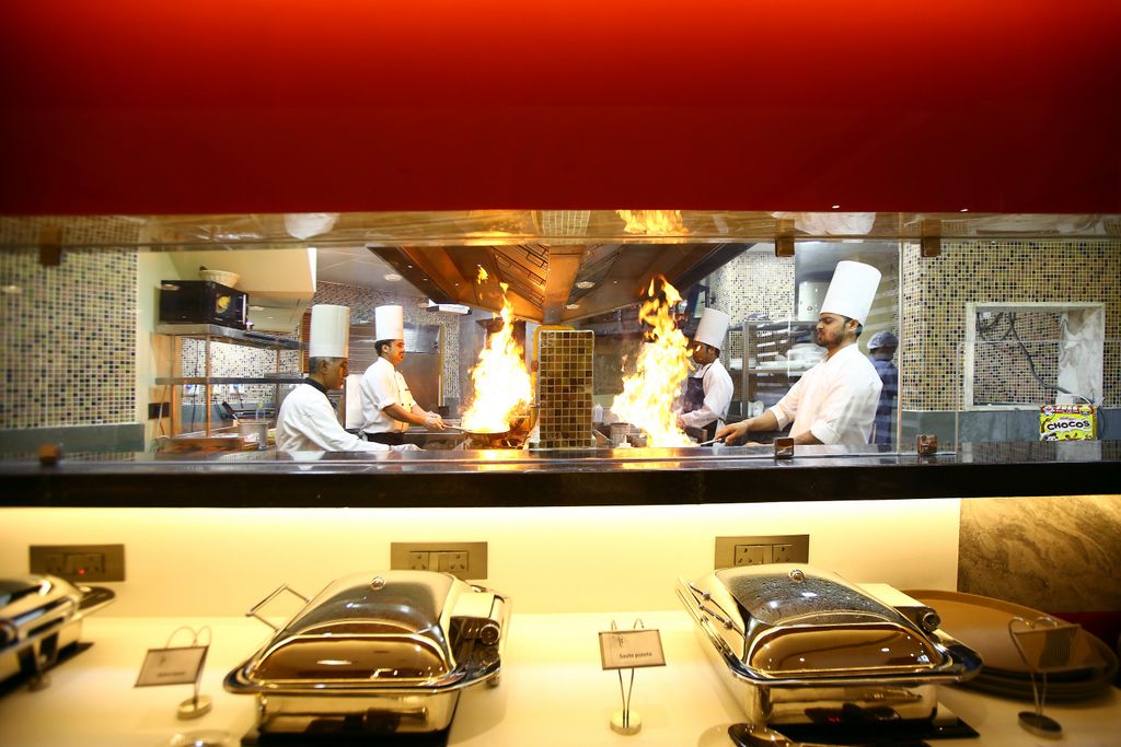 A restaurant with chefs performing a fire act. There are two car-shaped dessert displays in front.