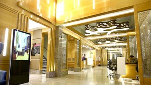 Eine Hotelhalle mit einer Rezeption, einem digitalen Informationskiosk und einer Treppe.