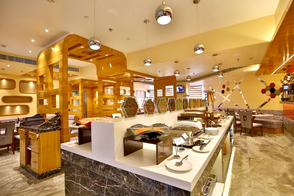 Un hall d’hôtel moderne avec un comptoir d’accueil en marbre, des éléments décoratifs en bois et un espace buffet.