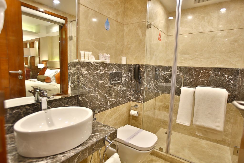 A modern bathroom with a marble sink, a toilet, and a glass-enclosed shower.