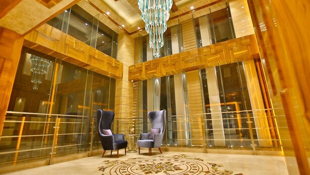 Eine geräumige Lobby mit hohen Decken, einem großen Chandelier und zwei Sesseln.