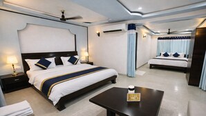 Una habitación de hotel con una cama grande, una cama más pequeña, una mesita de centro y una mesita de noche con una lámpara.