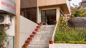 Un edificio moderno con una zona de recepción, una escalera con plantas en macetas y un jardín de rocas.