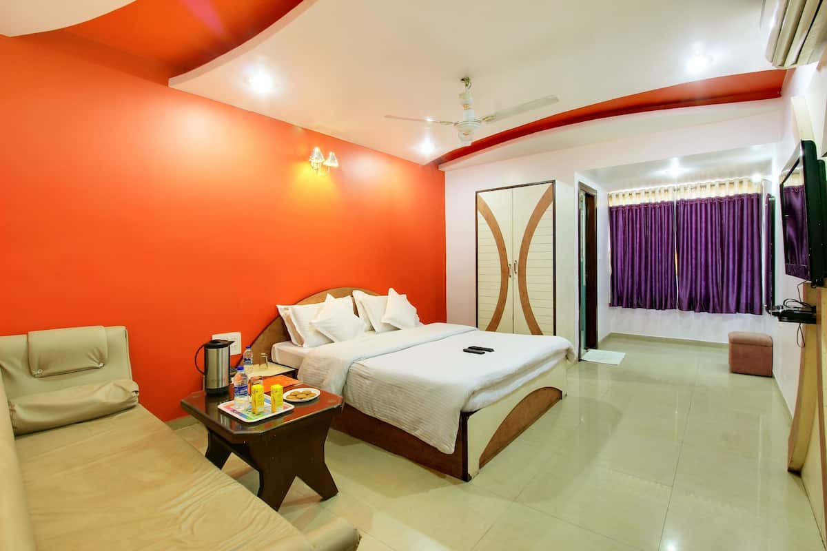 A hotel room with a bed, bedside table, chair, and a small table with food items.