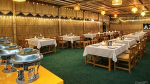 Un restaurante con varias mesas, cada una cubierta con un mantel blanco y rodeada de sillas de madera.
