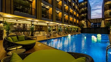 A hotel with a swimming pool, outdoor seating, and a bar area.