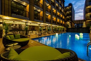 Un hotel con piscina, zona de estar al aire libre y bar.
