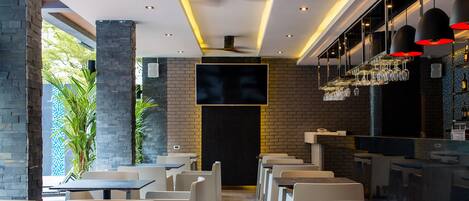 A restaurant with a modern interior, featuring brick walls, white chairs, and a bar area with hanging lights.