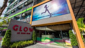 Un edificio moderno con un amplio frente de vidrio, balcones y un letrero destacado que dice "GLOW AO NANG KABI".