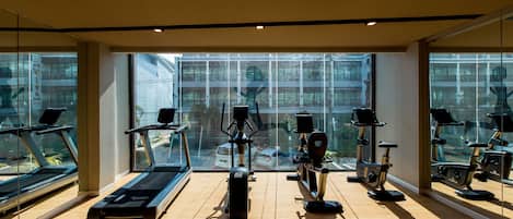 Un gimnasio con cintas de correr, elípticas y bicicletas estáticas.