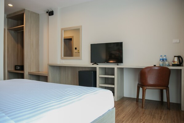 Una habitación de hotel con cama, televisión, escritorio con silla y armario.