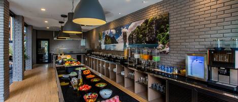 A modern breakfast bar with a variety of food options, a coffee station, and a mural on the wall.