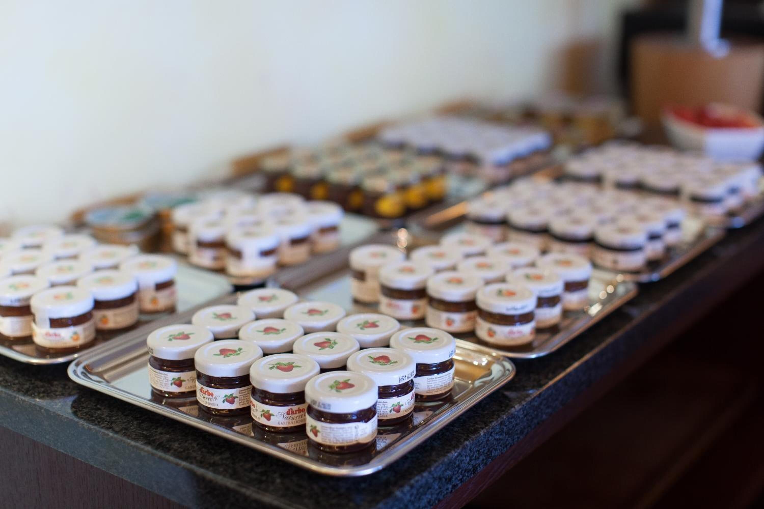 A buffet table with various food items, including jars of jam and other desserts.