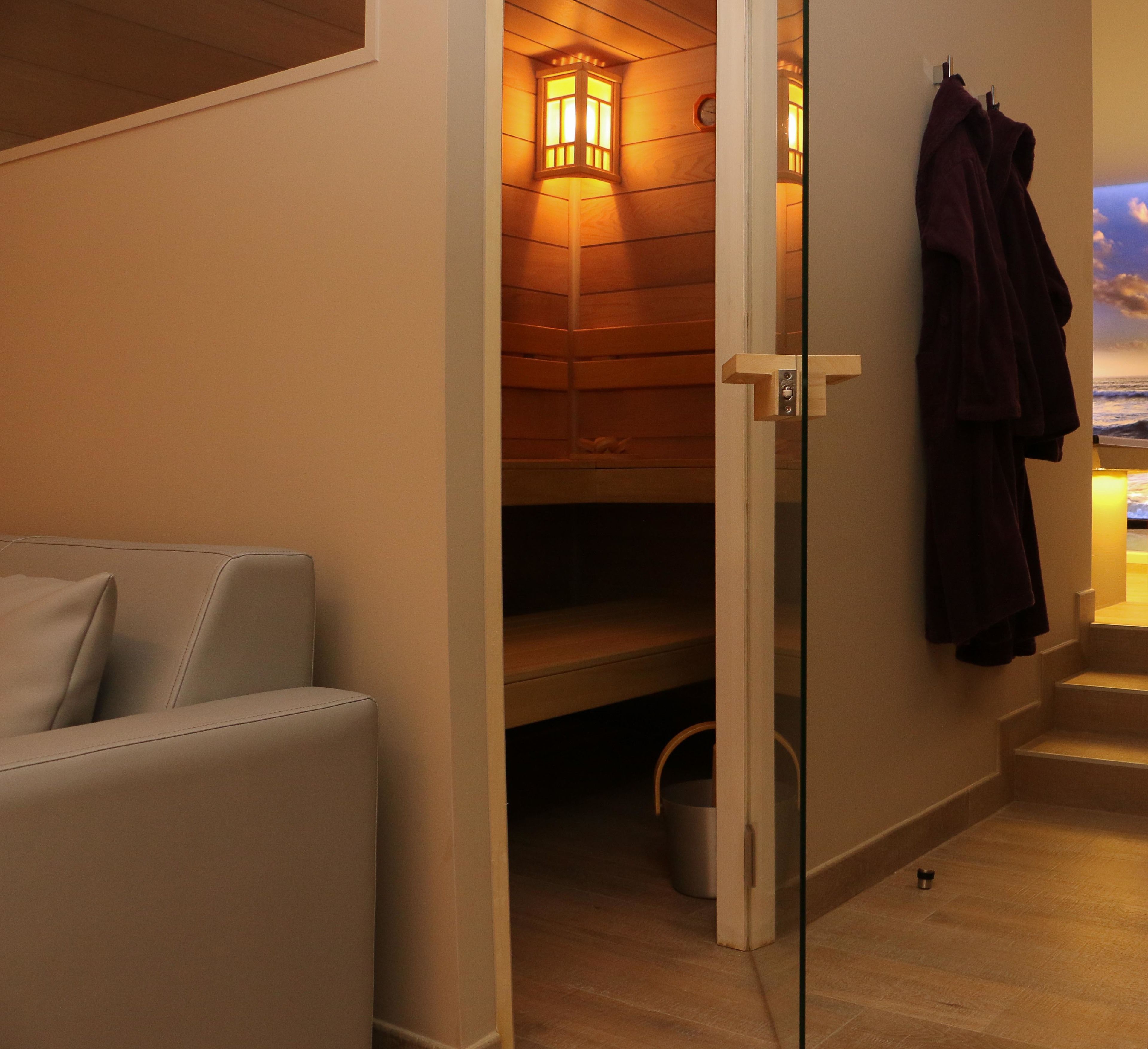 A sauna room with wooden walls, a bench, and towels hanging on the wall.