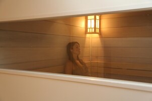 Une personne se trouve dans un hammam, et un luminaire est fixé au mur.