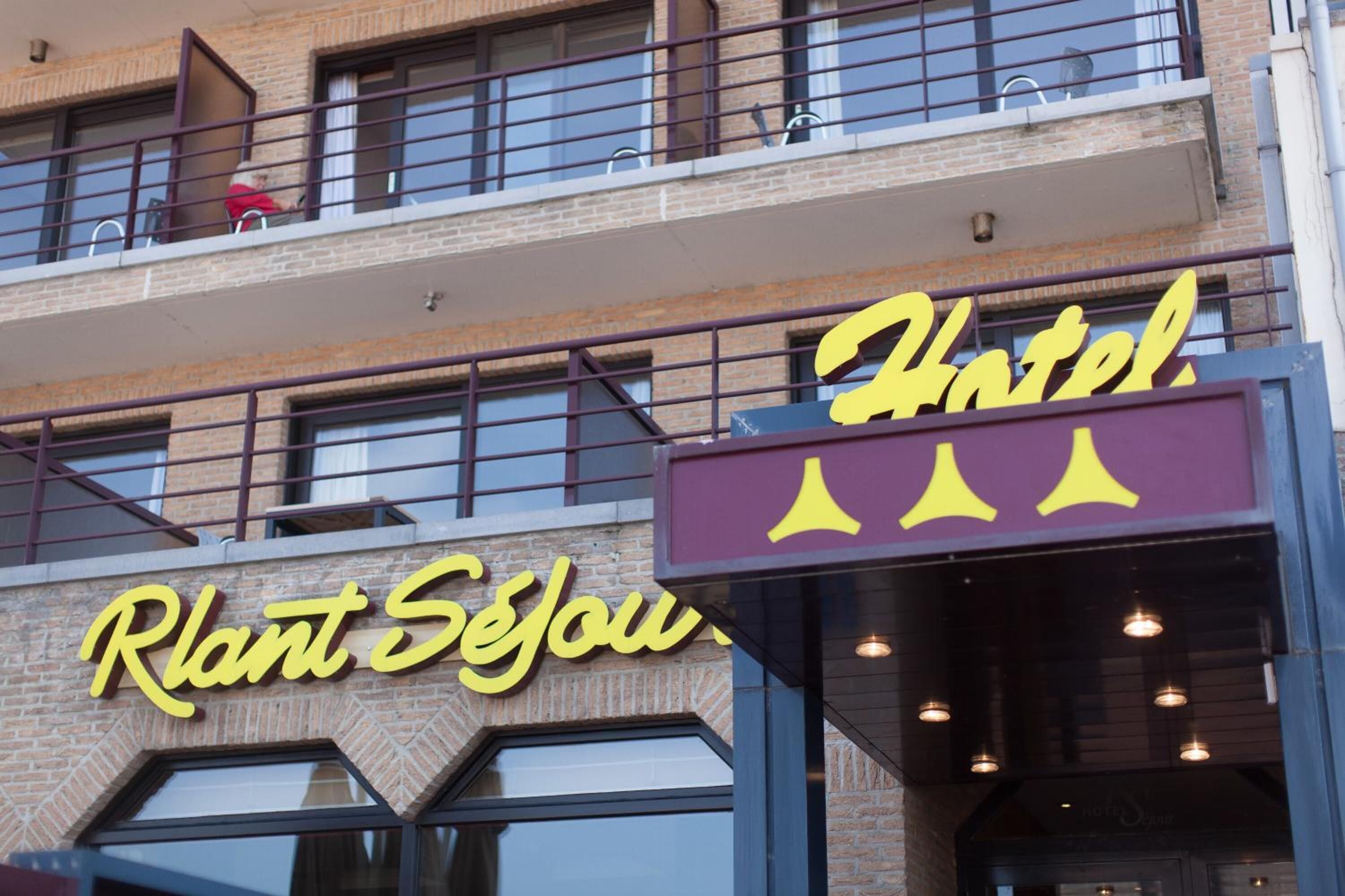 A hotel with a sign reading "Plant Sejou" and "Hotel" in yellow letters.