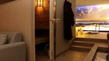Un cuarto de spa con pared de madera, una camilla de masaje y vista al océano al atardecer.