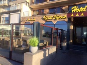 A hotel entrance with a glass facade, a potted plant, and a sign that reads "Hotel Plant Sejou." - Hotel Riant Séjour by WP Hotels  (Blankenberge)