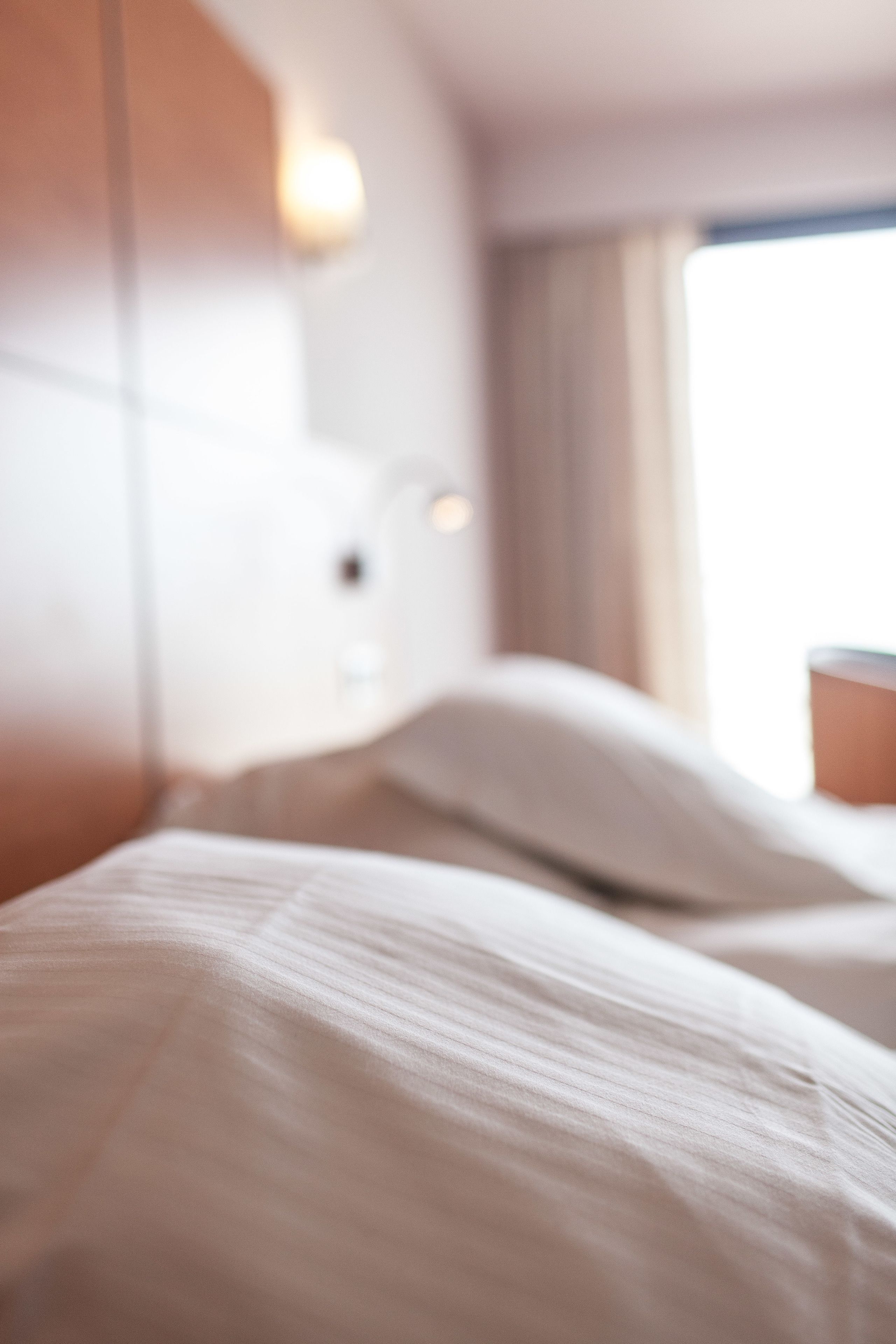 Una camera d'albergo con un letto, cuscini e un comodino.
