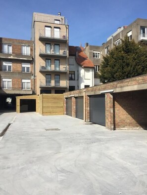 Een meerlaags woongebouw met een parkeerplaats ervoor.