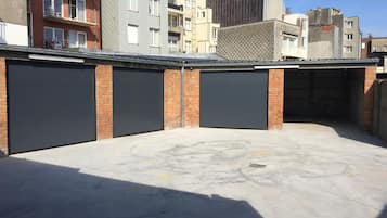 Ein Parkplatz mit drei geschlossenen Garagentoren, umgeben von mehrstöckigen Gebäuden.