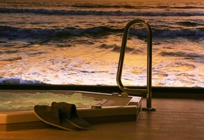 A bathtub with a view of ocean waves through a window.