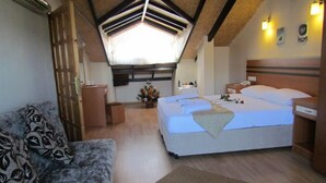 A cozy bedroom with a large bed, a sofa, a desk, and a small table with a flower vase. - Dalyan Palmiye Resort (Ortaca)