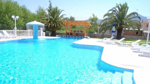 A swimming pool with a wooden gazebo, lounge chairs, and palm trees. - Dalyan Palmiye Resort (Ortaca)