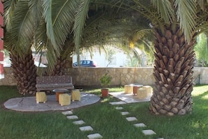 A patio area with palm trees, a stone wall, and outdoor furniture.