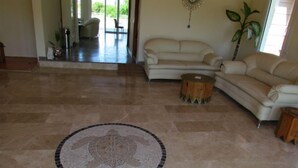 A spacious living area with a large beige sofa, a round wooden coffee table, and a decorative circular tile with a turtle design on the floor. - Dalyan Palmiye Resort (Ortaca)