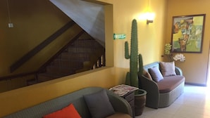 A living area with a sofa, a chair, a cactus, and a painting on the wall. - Ocean Lake Tourist Residence (Grand-Baie)