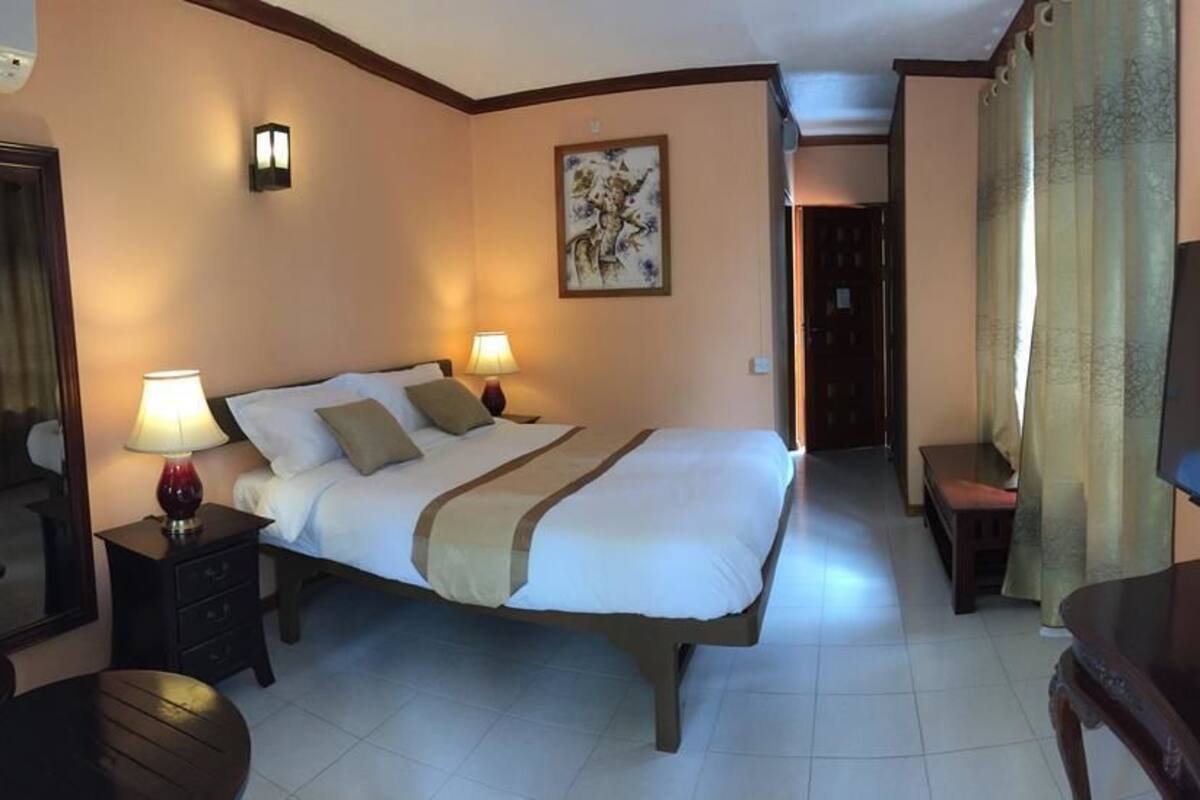A hotel room with a large bed, bedside lamps, a TV, a desk, and a chair.