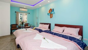 A hotel room with two beds, a sitting area with chairs, a small table, and an air conditioning unit. - Rose Garden Homestay Da Nang 2 - Hostel (Da Nang)