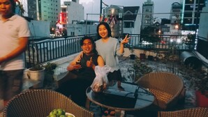 A rooftop terrace with wicker furniture, a table with a glass top, and potted plants. - Rose Garden Homestay Da Nang 2 - Hostel (Da Nang)