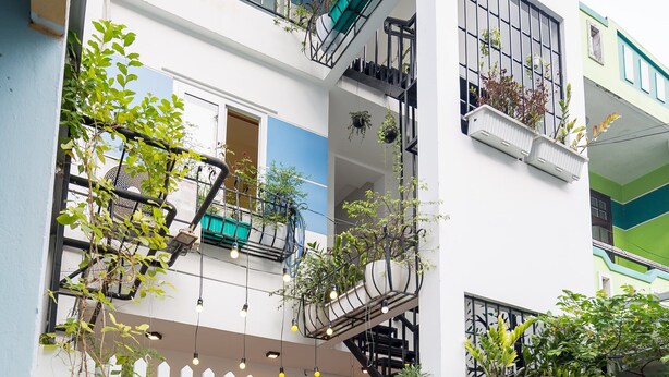 A multi-story building with balconies, potted plants, and a white picket fence. - Rose Garden Homestay Da Nang 2 - Hostel (Da Nang)