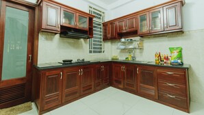 A kitchen with wooden cabinets, a black countertop, and a window with a white frame. - Urban House Saigon 2 (Ho Chi Minh City)