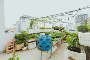 A rooftop garden with various potted plants and a blue barrel. - Urban House Saigon 2 (Ho Chi Minh City)