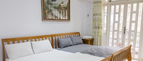A bedroom with a wooden bed, white and gray bedding, a nightstand, and a painting on the wall.