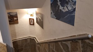 Una escalera con paredes de piedra, una barandilla y tres cuadros enmarcados en la pared.