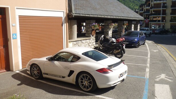 Un Porsche blanco estacionado en un espacio de estacionamiento con montañas al fondo.