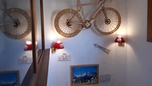Pared con una bicicleta de madera, dos lámparas rojas y un cuadro con una montaña.