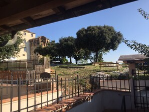 A courtyard with a fountain, a wooden fence, and a building with a stone facade.